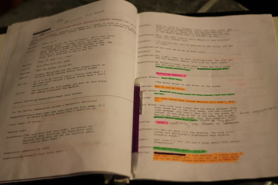 An open playscript densely annotated in several colors of highlighter.